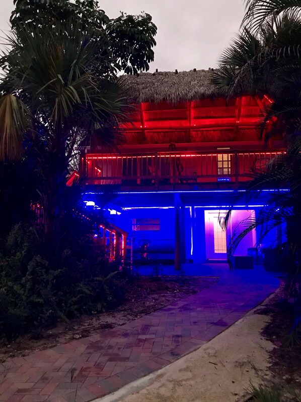 Edificio con techo de paja y balcón, rodeado de vegetación tropical.