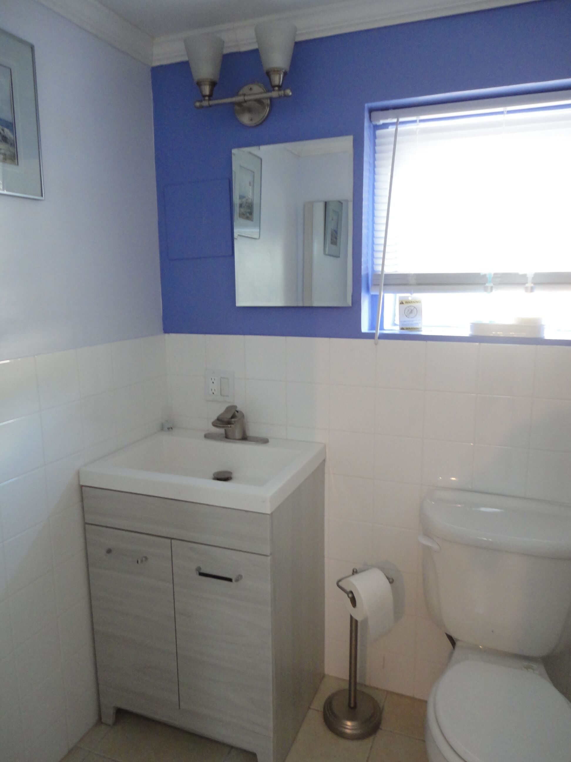Ein Badezimmer mit einem weißen Waschbecken, einer Toilette und einem Spiegel über dem Waschbecken.