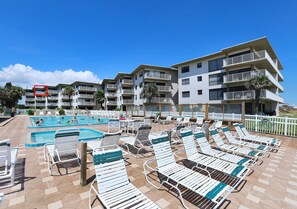 Un espace piscine d’hôtel comprenant plusieurs chaises longues et une piscine.