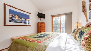 A bedroom with a bed, a dresser, a TV, and a window. - Home Away From Home in Snowcreek V Resort (Mammoth Lakes)