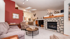 A living room with a stone fireplace, a round coffee table, and a sofa. - Home Away From Home in Snowcreek V Resort (Mammoth Lakes)