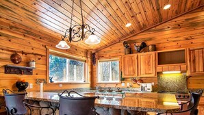 Una cocina rústica con paredes de madera, una barra de piedra y un ventanal grande.