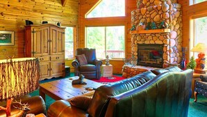 Interior acogedor de una cabaña con chimenea de piedra, paredes de madera y un sofá de cuero.