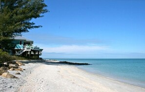 Ein Strandhaus mit Veranda mit Blick aufs Meer.