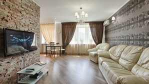 A living room with a TV, leather sofa, and a brick wall. - Clean, Safe and Affordable (Pechers'kyi district)