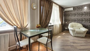 A dining area with a glass table, four chairs, a vase with flowers, and a clock on the wall. - Clean, Safe and Affordable (Pechers'kyi district)
