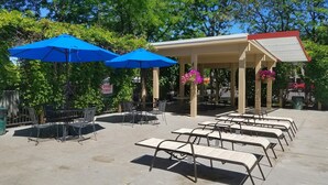 An outdoor patio with tables and chairs, blue umbrellas, and hanging flower baskets.