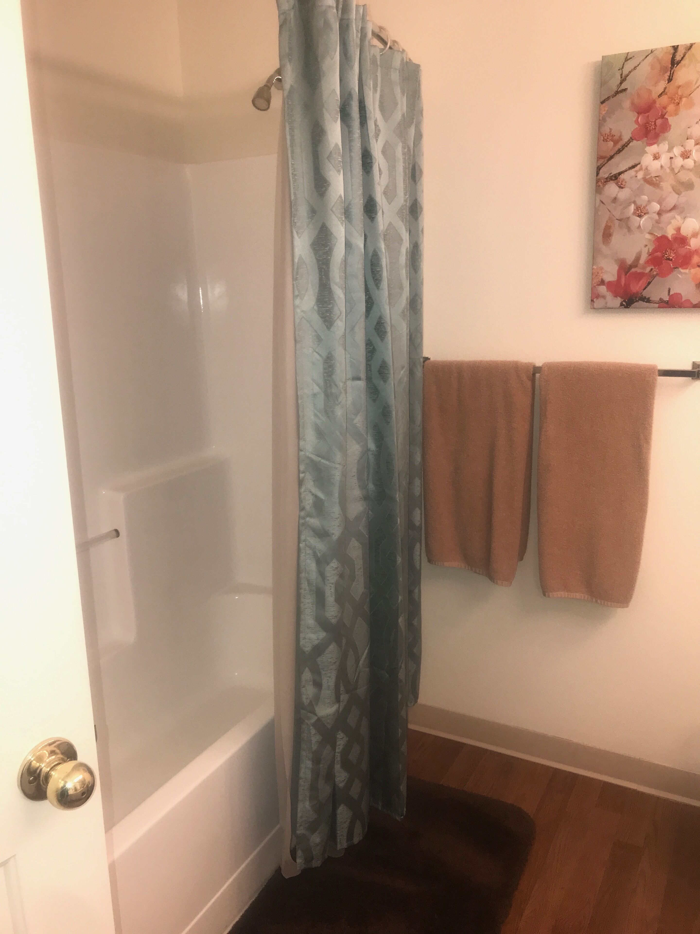 A bathroom with a shower curtain, a bathtub, and a towel rack with towels.
