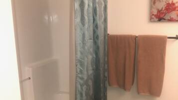 A bathroom with a shower curtain, a bathtub, and a towel rack with towels.