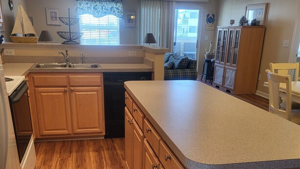A modern kitchen with wooden cabinets, a built-in dishwasher, and a granite countertop. - 1206 Palms, 3-bedroom, 2-bath condo, Sept dates at last minute & off-season rate (Rehoboth Beach)