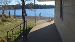 Un paseo techado que conduce a un lago, con vista al agua y árboles al fondo.
