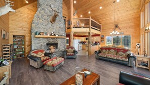 A spacious lodge with a stone fireplace, wooden floors, and a loft area. - Tranquil Country Lodge Getaway with Hot Tub!  Privacy & Serenity Abound... (Cheney)