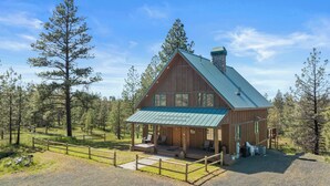 A rustic cabin with a metal roof, wooden exterior, and a porch with seating. - Tranquil Country Lodge Getaway with Hot Tub!  Privacy & Serenity Abound... (Cheney)