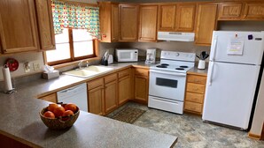 A kitchen with wooden cabinets, a white refrigerator, a stove, and a microwave.