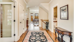 Un couloir avec un plancher en bois, un tapis à motifs, un escalier et une statue d’ours.