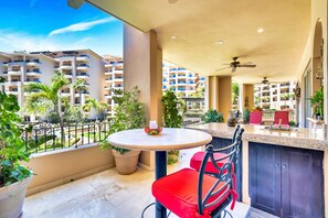 A balcony with a round table, red chairs, and a view of other buildings.