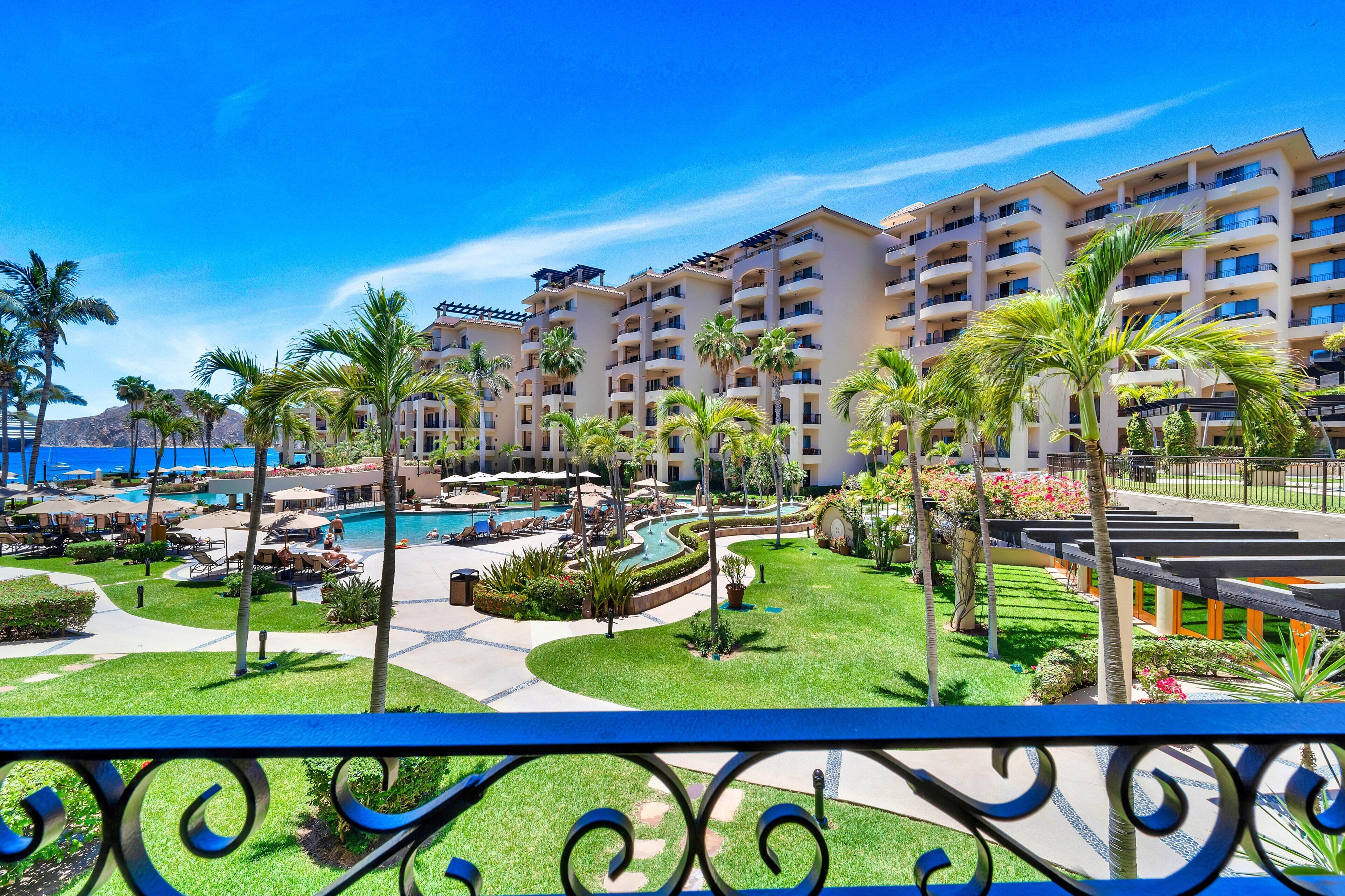 A hotel with multiple balconies, a swimming pool, and a landscaped garden.