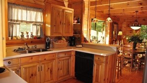 Eine holzgetäfelte Küchenzeile mit Holzschränken, einem Geschirrspüler und einem Essbereich mit Tisch und Stühlen.