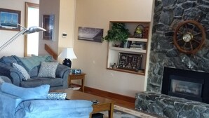 Un salon avec un canapé, une table basse, une cheminée et un mur en pierre.