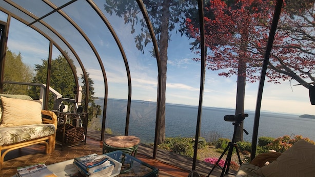 Une pièce avec une table en verre, un canapé et une vue sur la mer.