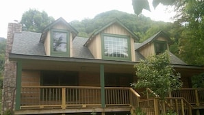 A two-story wooden cabin with a balcony and a small porch.
