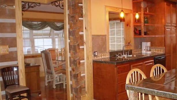 A kitchen with wooden cabinets, a granite countertop, and a dining area with chairs.
