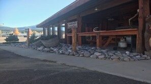 Situated in a natural setting, this cabin offers a covered porch area for outdoor seating and a stone pathway leading to the entrance.