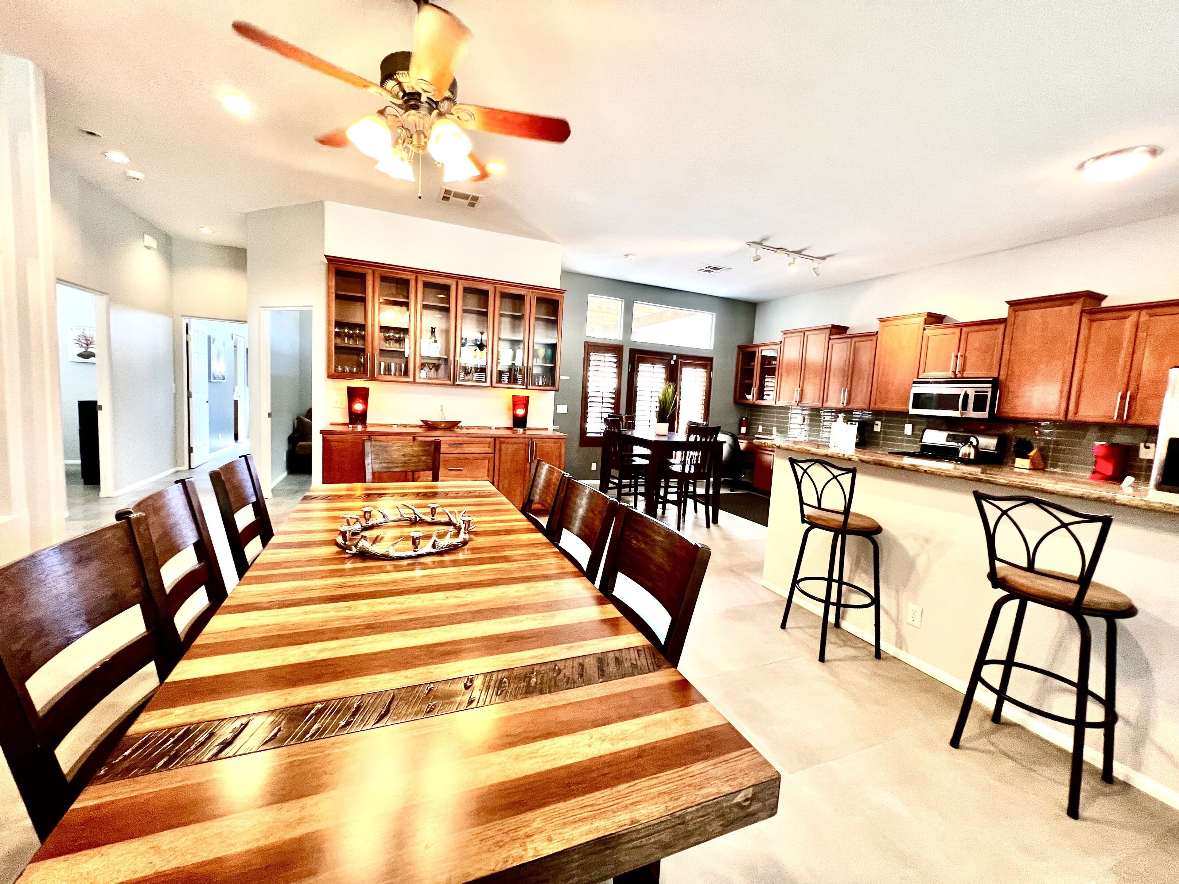 A spacious dining area with a wooden table and chairs, a kitchen with wooden cabinets, and a ceiling fan.