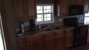 A kitchen with wooden cabinets, a microwave, a stove, and a sink. - Secluded, Log Rental Cabin, Private Hot Tub,on Southern Illinois Wine Trail (Buncombe)