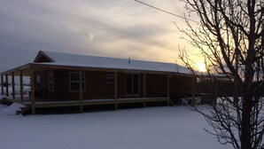 A wooden cabin with a covered porch, surrounded by snow. - Secluded, Log Rental Cabin, Private Hot Tub,on Southern Illinois Wine Trail (Buncombe)