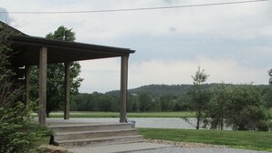 A covered outdoor area with steps leading to a bench, surrounded by a gravel path and greenery. - Secluded, Log Rental Cabin, Private Hot Tub,on Southern Illinois Wine Trail (Buncombe)