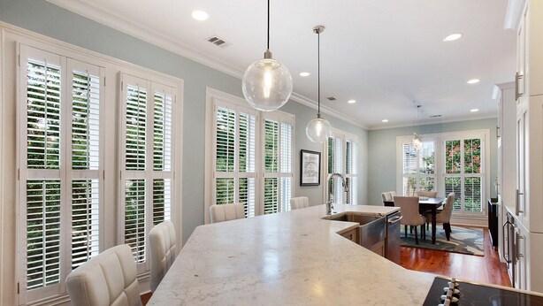 A kitchen with a marble island, white cabinetry, and a dining area with a table and chairs. - Wright Square Loft: Amazing Unit A in Downtown Savannah With Great Views! (Savannah)