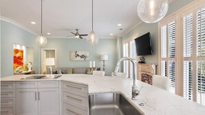 A modern kitchen with a central island, stainless steel sink, pendant lights, and a ceiling fan. - Wright Square Loft: Amazing Unit A in Downtown Savannah With Great Views! (Savannah)