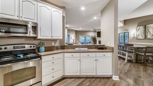 A modern kitchen with white cabinetry, a stainless steel stove, and a granite countertop. - Perfect Family Home w/ Pool & Lagoon Views (Hilton Head Island)