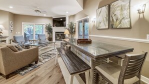 A spacious living room with a large glass-top dining table, comfortable seating, and a fireplace. - Perfect Family Home w/ Pool & Lagoon Views (Hilton Head Island)