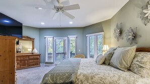 A bedroom with a bed, a ceiling fan, a dresser, a TV, and a balcony with sliding doors. - Perfect Family Home w/ Pool & Lagoon Views (Hilton Head Island)