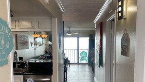 A kitchen with a stainless steel refrigerator, a dining area with a chair, and a view of a balcony. - Beautiful  2 Bedroom Vacation Condo in Galveston - Great Gulf Views   (Galveston)