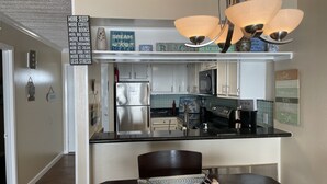 A modern kitchen with stainless steel appliances, a black countertop, and decorative signs. - Beautiful  2 Bedroom Vacation Condo in Galveston - Great Gulf Views   (Galveston)