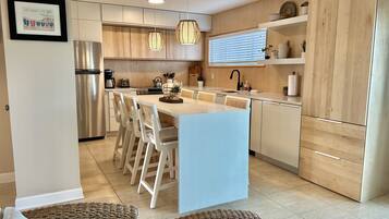 A modern kitchen with a central island, stainless steel appliances, and wooden cabinetry.