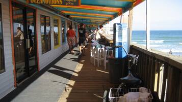 A pier with a colorful awning, a shop named 'Oceanotions' selling tropical gifts, and a view of the ocean.