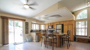 A spacious kitchen with a central island, wooden cabinets, and a large window providing natural light. - BRAND NEW, PRISTINE HAVEN WITH SALT WATER  POOLS (Palm Springs)