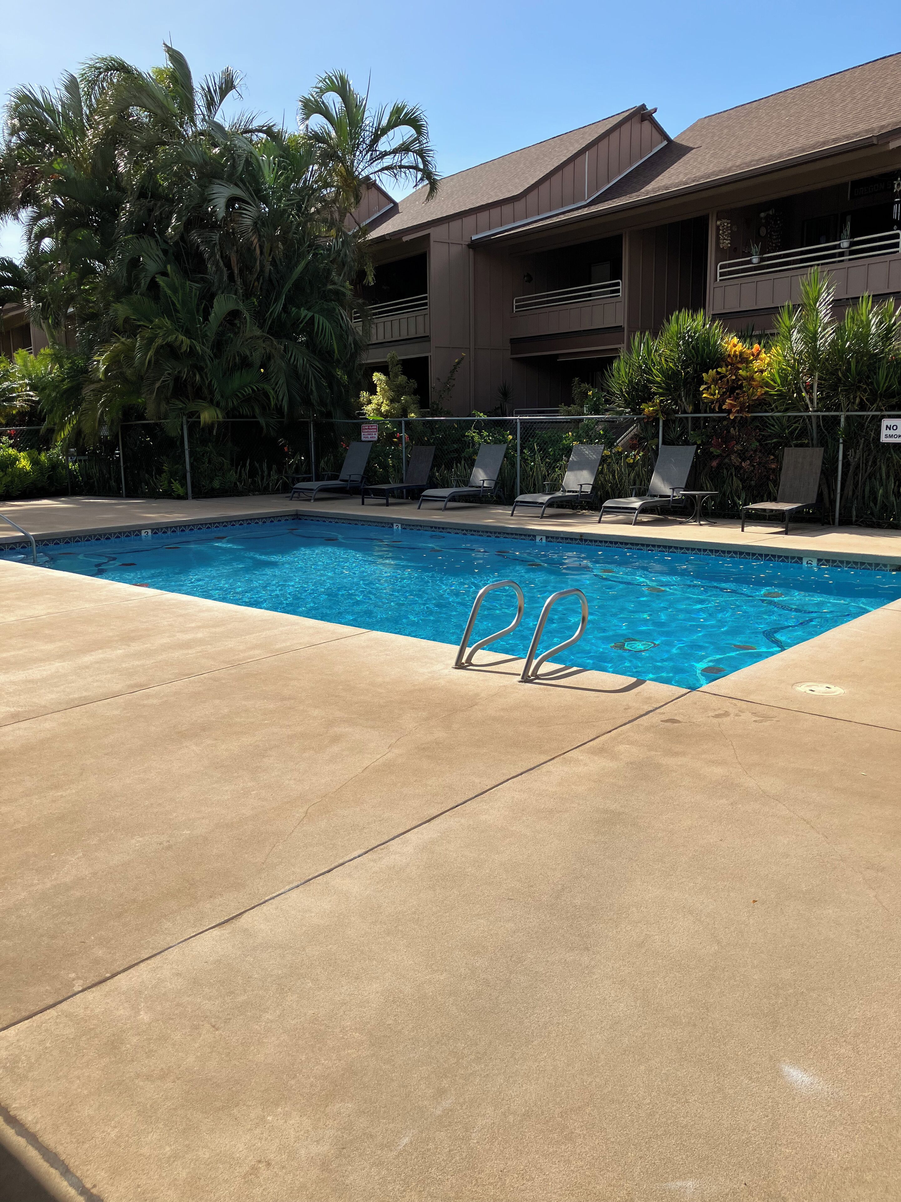 A swimming pool with lounge chairs and a building in the background.