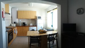 Una cucina funzionale con mobili in legno, un forno a microonde, una lavatrice e un'area pranzo con tavolo e sedie.