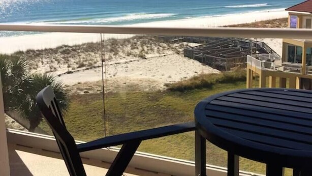 Ein Balkon mit Blick auf den Strand, einem Tisch und Stühlen.