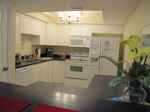 Una cocina con armarios blancos, microondas, horno y refrigerador.