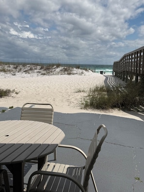 A beachside seating area with a view of the ocean and a wooden boardwalk.