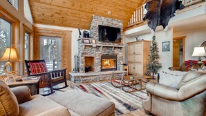 A cozy living room with a stone fireplace, leather sofas, and a television mounted above it. - Log Home, Hot Tub & Pool-Table Game Room - 25 mi to Breckenridge (Fairplay)