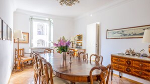 Une salle à manger avec une table en bois, des chaises, un lustre et un vase de fleurs.