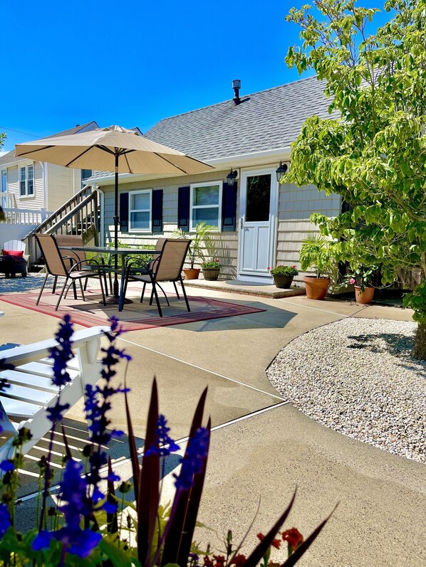A patio area with a table and chairs, a covered seating area, and potted plants.