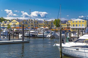 A marina with several yachts docked, surrounded by yellow buildings with balconies.
